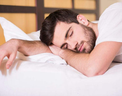 A person with night sweats sleeps soundly on cooling sheets.