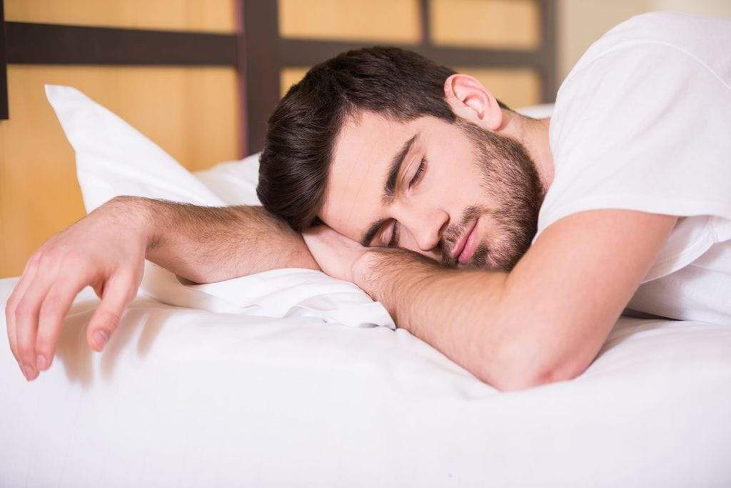 A person with night sweats sleeps soundly on cooling sheets.
