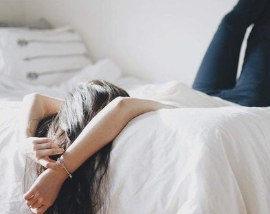 A woman lounges in her clean bed sheets.